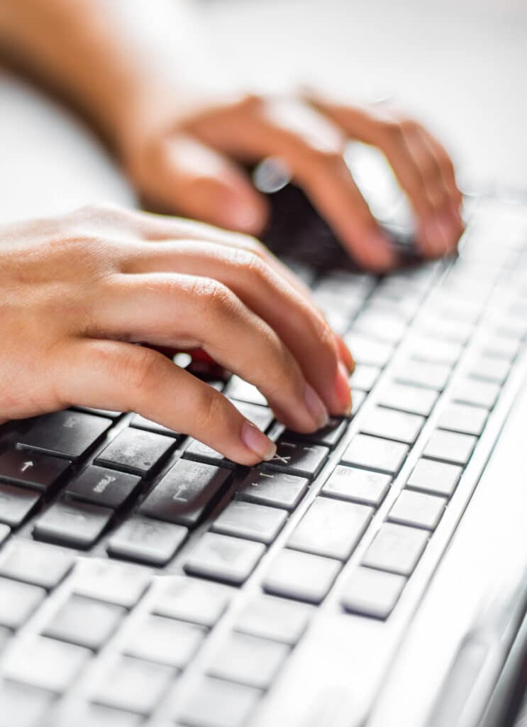 Mains tapant sur un clavier d'ordinateur portable noir. Les doigts sont positionnés sur les touches Ctrl, Shift et Pause, avec une main à droite.