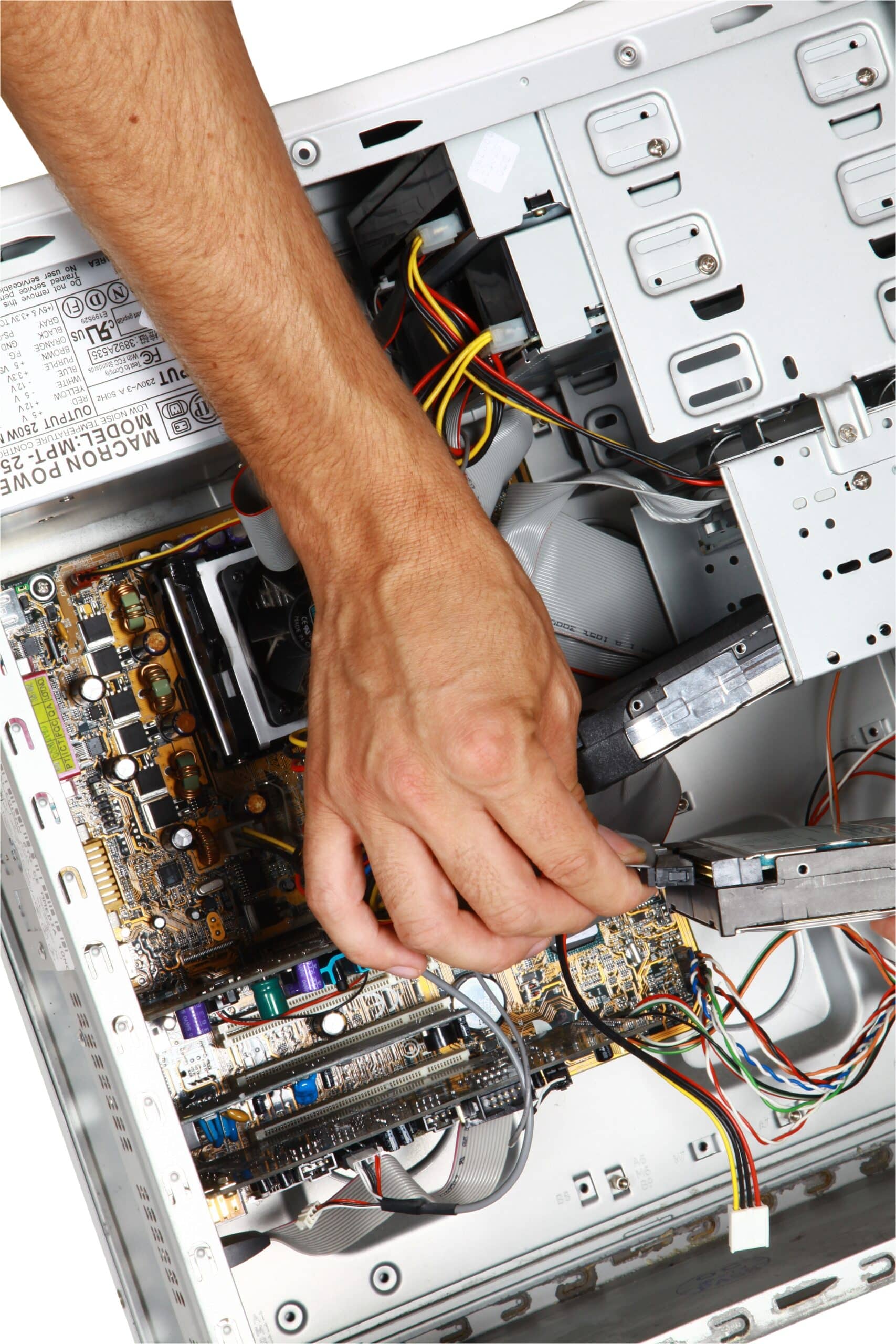 Main d'un technicien connectant un câble à un disque dur dans une tour PC ouverte. Carte mère et alim. MACRON POWER MPT-250WN. Maintenance PC.
